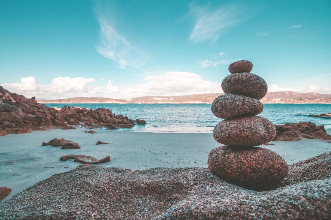 A pile of stones balance on top of each other on a beach.